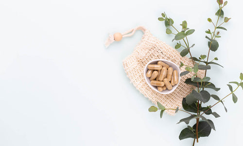 Doplňky stravy pro ženy na bílém pozadí, označená jako vitamíny pro hormonální rovnováhu a energii.
